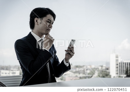 年輕的亞洲商人在辦公室檢查他的智慧型手機（單色/黑白） 122070451