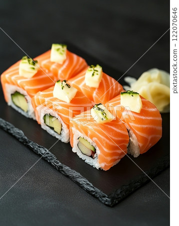 Fresh salmon sushi rolls with avocado and pineapple on black slate plate. 122070646