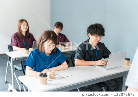 Male and female medical staff in scrubs attending medical conferences, study sessions, seminars, training sessions Male and female medical staff in scrubs attending medical conferences, study sessions, seminars, training sessions 122072672