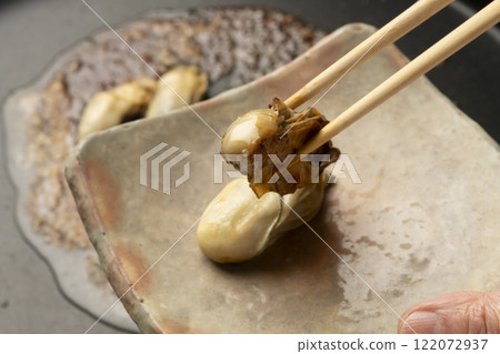 將鐵板上烤好的生蠔擺在盤子上。 將鐵板上烤好的生蠔擺在盤子上。 122072937