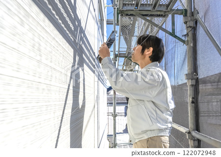 一名男子正在檢查獨立屋外牆維修工作的進展 一名男子正在檢查獨立屋外牆維修工作的進展 122072948