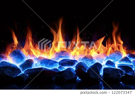 Vibrant flames rising from glowing blue rocks in the dark 122073347