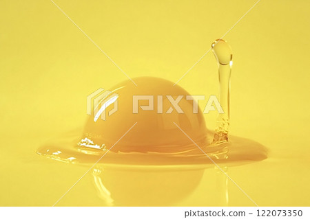Yellow liquid splashing into a dome on yellow background 122073350