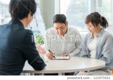 一對夫婦在聆聽，一位商人在陳列室/商務談判空間為客戶提供服務 122073832