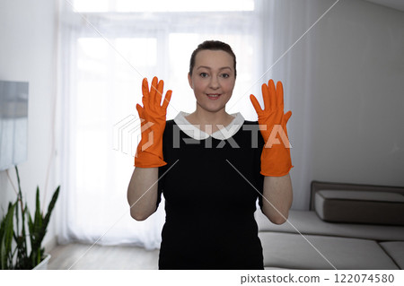 The maid in bright orange rubber gloves is fully ready to start cleaning. 122074580