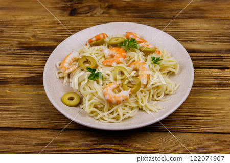 Spaghetti pasta with prawns, green olives and parsley on wooden table 122074907