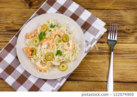 Spaghetti pasta with prawns, green olives and parsley on wooden table. Top view 122074908