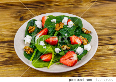 Fresh healthy salad with strawberry, spinach, walnuts and feta cheese on wooden table 122074909