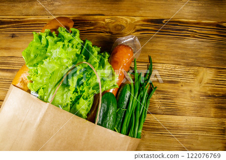 Paper bag with different food on wooden table. Top view. Grocery shopping concept Paper bag with different food on wooden table. Top view. Grocery shopping concept 122076769