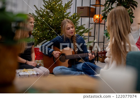 A Cozy Gathering Friends Joyfully Singing with a Guitar in a Warm and Festive Setting 122077074