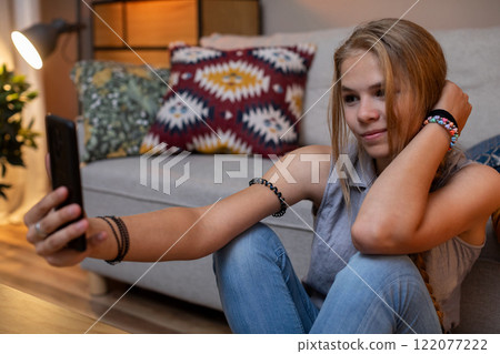A Teenage Girl is Enjoying Taking a Selfie in a Cozy and Inviting Living Room Setting A Teenage Girl is Enjoying Taking a Selfie in a Cozy and Inviting Living Room Setting 122077222