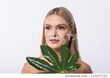 This is a captivating portrait of a Woman holding a Leaf set against a pristine White Background This is a captivating portrait of a Woman holding a Leaf set against a pristine White Background 122077225