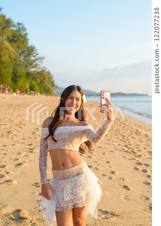 Young Thai Woman Vlogging on Smartphone at a Tropical Beach During Sunset Young Thai Woman Vlogging on Smartphone at a Tropical Beach During Sunset 122077238