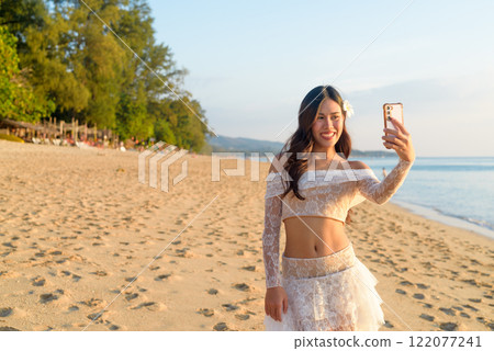 Influencer Lifestyle Woman Creating Content on Tropical Beach at Dusk 122077241