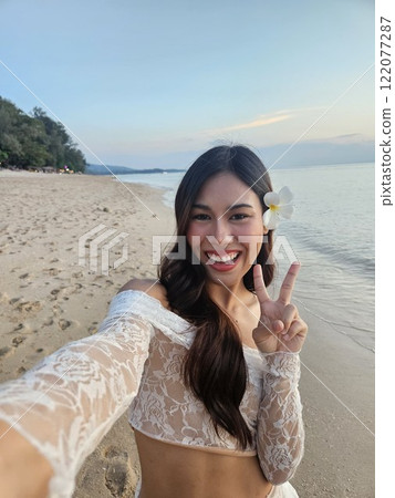Woman on the beach taking selfie 122077287