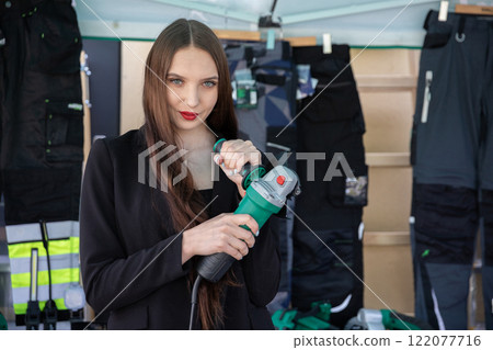 A model is showcasing innovative construction tools while dressed in fashionable and trendy attire A model is showcasing innovative construction tools while dressed in fashionable and trendy attire 122077716