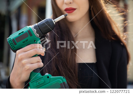 A Confident Woman Holding a Power Drill Demonstrates Strength and Skill in Construction A Confident Woman Holding a Power Drill Demonstrates Strength and Skill in Construction 122077721