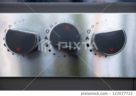 A closeup view of sleek stainless steel stove knobs featured prominently in a modern kitchen A closeup view of sleek stainless steel stove knobs featured prominently in a modern kitchen 122077722