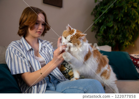A girl enjoying tender moments while bonding with her beloved cat in a cozy home setting 122077858