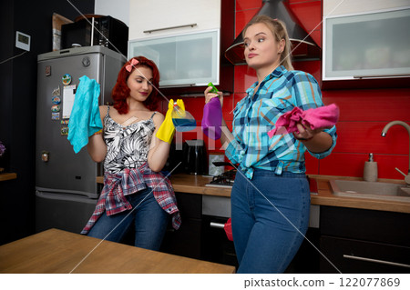 Young women in colorful outfits are joyfully enjoying themselves in a modern kitchen 122077869