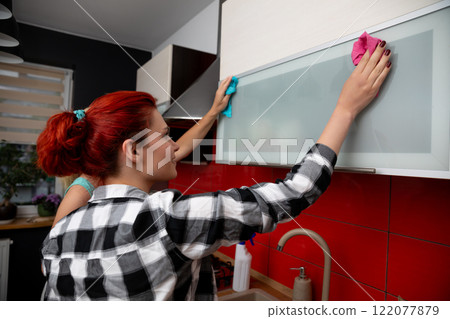 Two women collaborate to clean kitchen surfaces, fostering teamwork and a tidy environment Two women collaborate to clean kitchen surfaces, fostering teamwork and a tidy environment 122077879