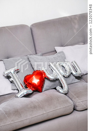 "I love you" from balloon setting on grey sofa. Theme of love. 122078348