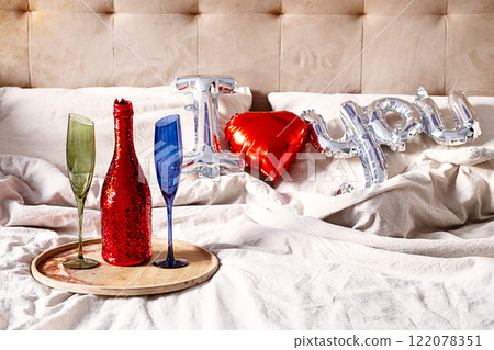 Champange bottle, two glasses and " I love you" balloon on the bed. Romantic concept. 122078351