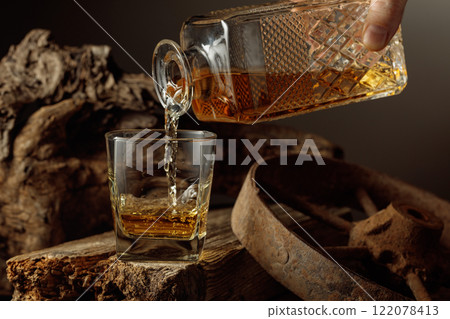 Whiskey is poured from a decanter into a glass. 122078413
