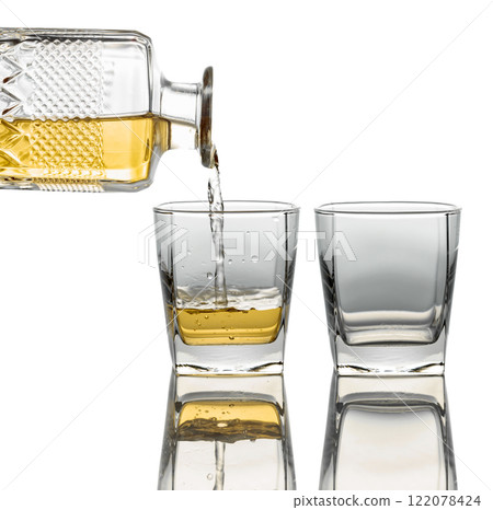 Pouring whiskey from a decanter into a glass on a white background. 122078424