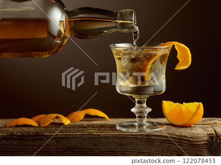 Old Fashioned cocktail with ice and orange peel on a old wooden table. Old Fashioned cocktail with ice and orange peel on a old wooden table. 122078455