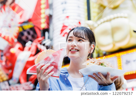 A woman eating the famous takoyaki and takosen in Dotonbori, Osaka A woman eating the famous takoyaki and takosen in Dotonbori, Osaka 122079257