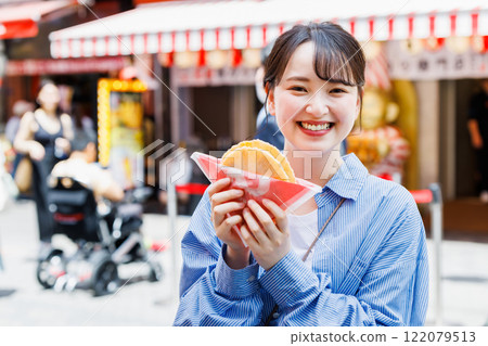 A woman eating the famous takosen in Dotonbori, Osaka A woman eating the famous takosen in Dotonbori, Osaka 122079513