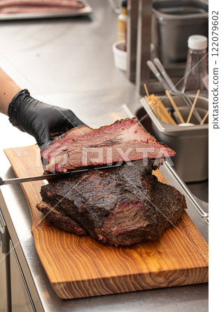 Cutting smoked brisket into slices in the kitchen Cutting smoked brisket into slices in the kitchen 122079602