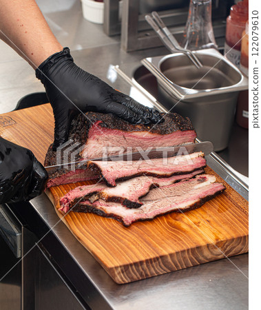 Cutting smoked brisket into slices in the kitchen 122079610