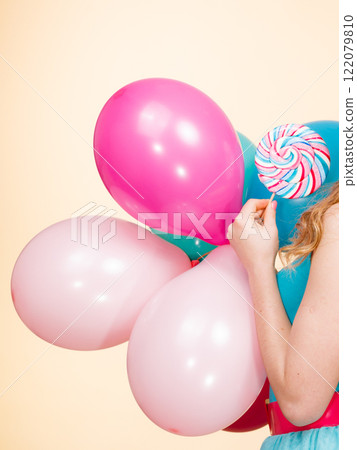 Woman holds colorful balloons and lollipop 122079810