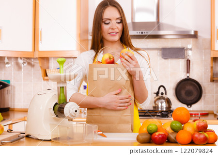 Woman in kitchen preparing fruits for juicing 122079824