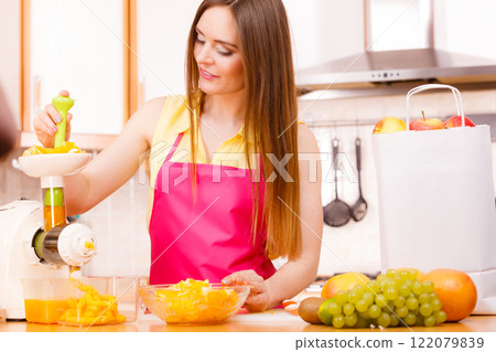 Woman making orange juice in juicer machine 122079839