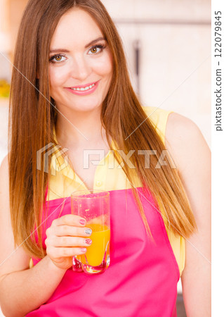 Woman in kitchen drinking fresh orange juice Woman in kitchen drinking fresh orange juice 122079845