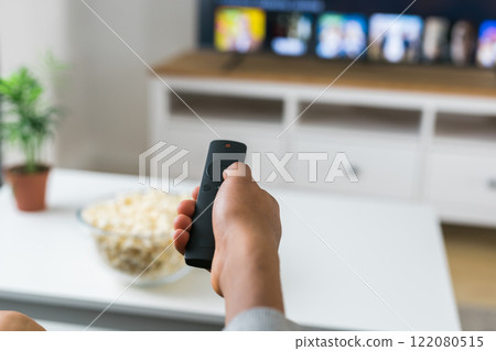 Remote control is pointed toward the television screen, control and choice of tv entertainment. TV, series and streaming service concept Remote control is pointed toward the television screen, control and choice of tv entertainment. TV, series and streaming service concept 122080515