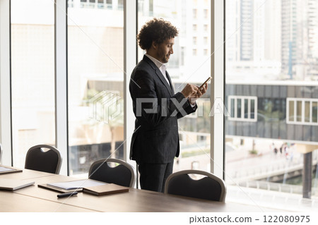 Arabic businessman typing message on mobile phone Arabic businessman typing message on mobile phone 122080975