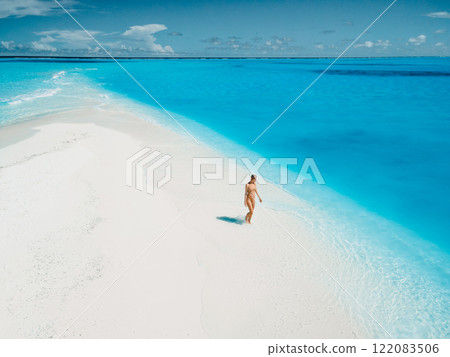 Woman on tropical white sandy beach with blue ocean water. Aerial view 122083506