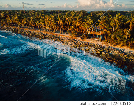 Coastline with palms and warm sunrise or sunset tones in tropical island Coastline with palms and warm sunrise or sunset tones in tropical island 122083510