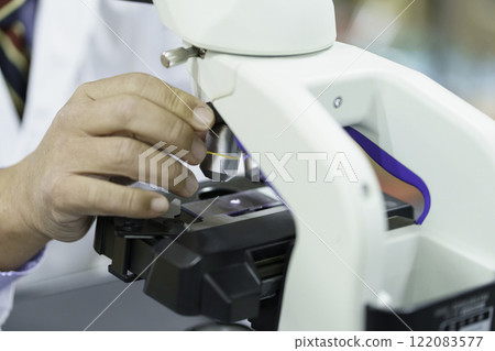 A close-up of the hands of a doctor in a white coat operating a microscope. Photo courtesy of Tokyo Electronics College, Denpa Gakuen Corporation A close-up of the hands of a doctor in a white coat operating a microscope. Photo courtesy of Tokyo Electronics College, Denpa Gakuen Corporation 122083577