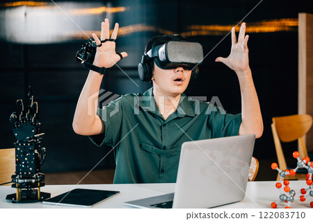 Asian teenager using VR glasses controls a robot arm project in a classroom. Merging robotics programming with STEM education exploring futuristic technology. moves a robotic hand 122083710