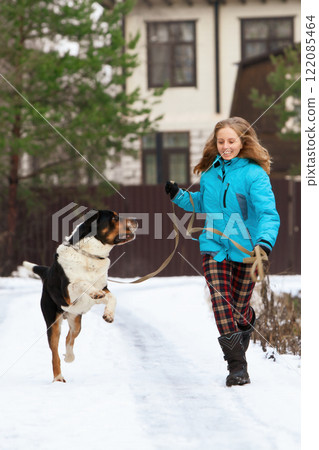 Smiling woman running with her sennenhund dog on snowy path, enjoying a winter walk. Capturing friendship, activity, and outdoor fun in cold and cheerful environment. Smiling woman running with her sennenhund dog on snowy path, enjoying a winter walk. Capturing friendship, activity, and outdoor fun in cold and cheerful environment. 122085464