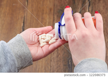 Young woman pouring pills into her palm. 122086373