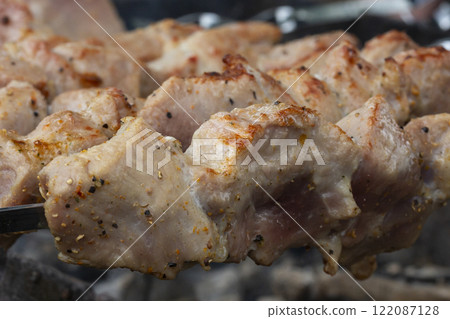 closeup of some meat skewers being grilled in a barbecue closeup of some meat skewers being grilled in a barbecue 122087128
