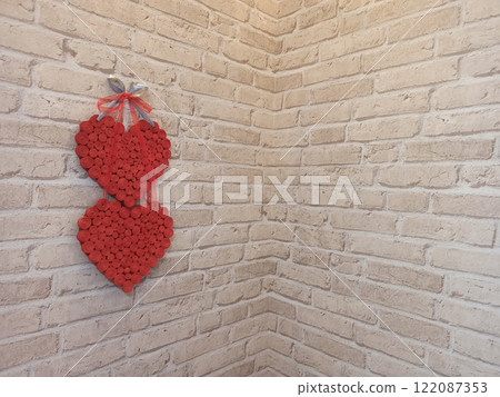 Red hearts hang on brick wall near corner of room. Symbol of love. Lovers symbol 122087353