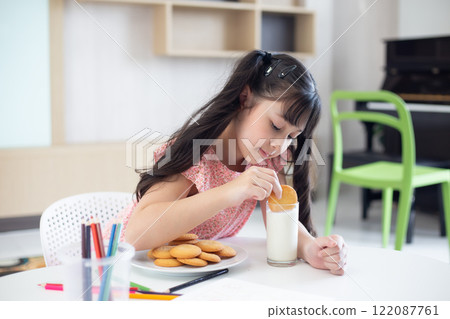 A girl is picking up a snack dipped in milk in the living room. A girl is picking up a snack dipped in milk in the living room. 122087761