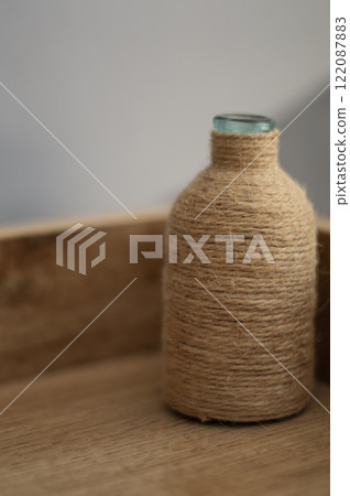A decorative wrapped twine glass bottle on the bedside table A decorative wrapped twine glass bottle on the bedside table 122087883